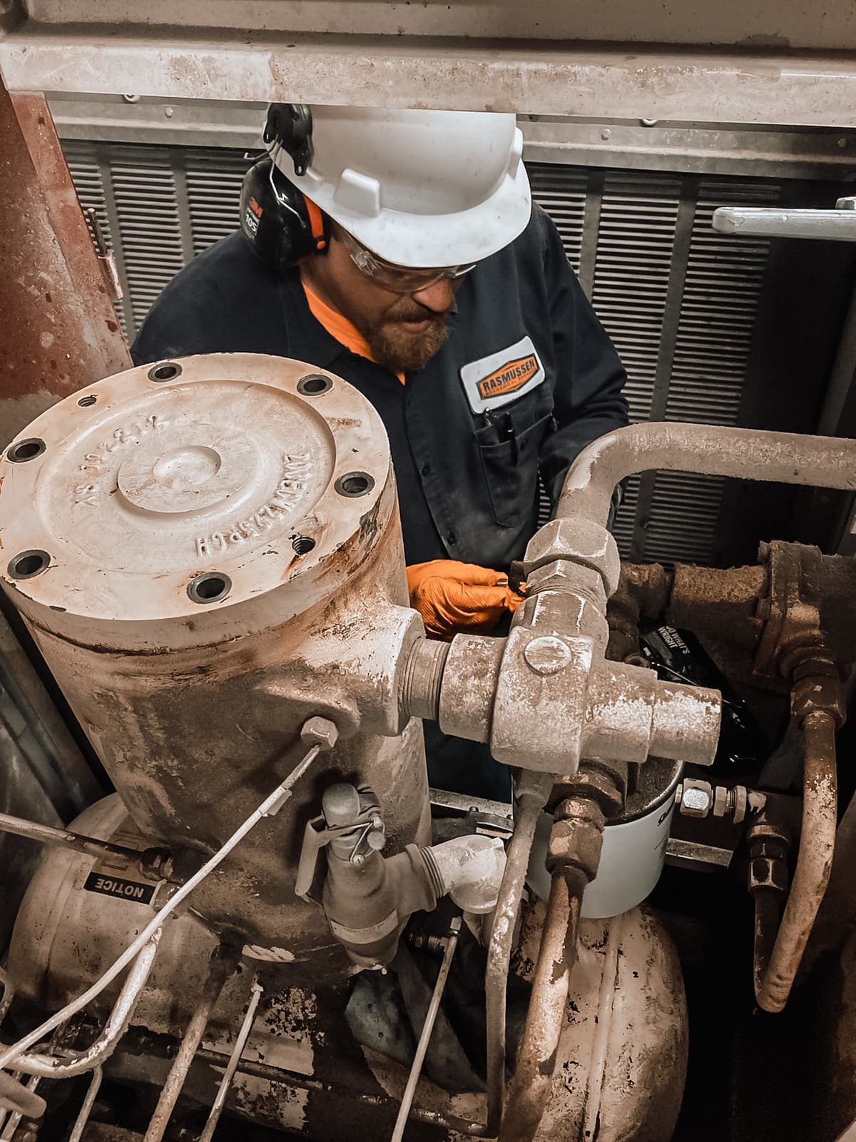 Rasmussen Mechanical technician conducting industrial air compressor inspection and maintenance work.