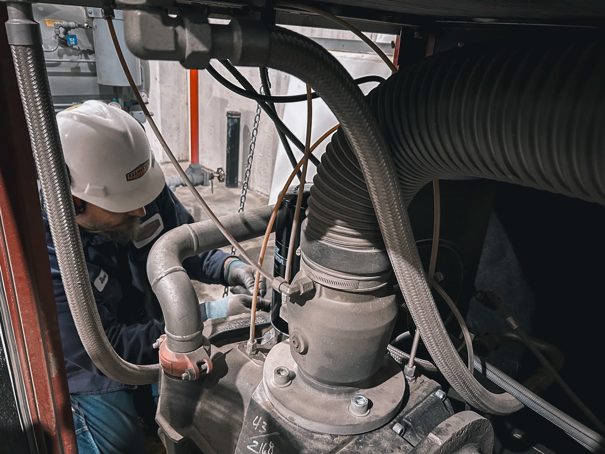 Rasmussen Mechanical technician conducting maintenance on industrial air compressor components.
