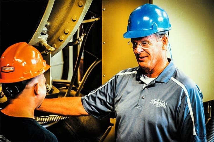 Bruce Rasmussen pointing out equipment in an industrial plant.