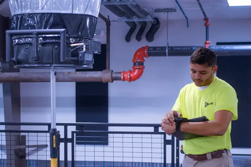 Rasmussen Mechanical Services technician performing HVAC airflow balancing and performance testing inside a commercial facility to ensure efficiency and compliance.