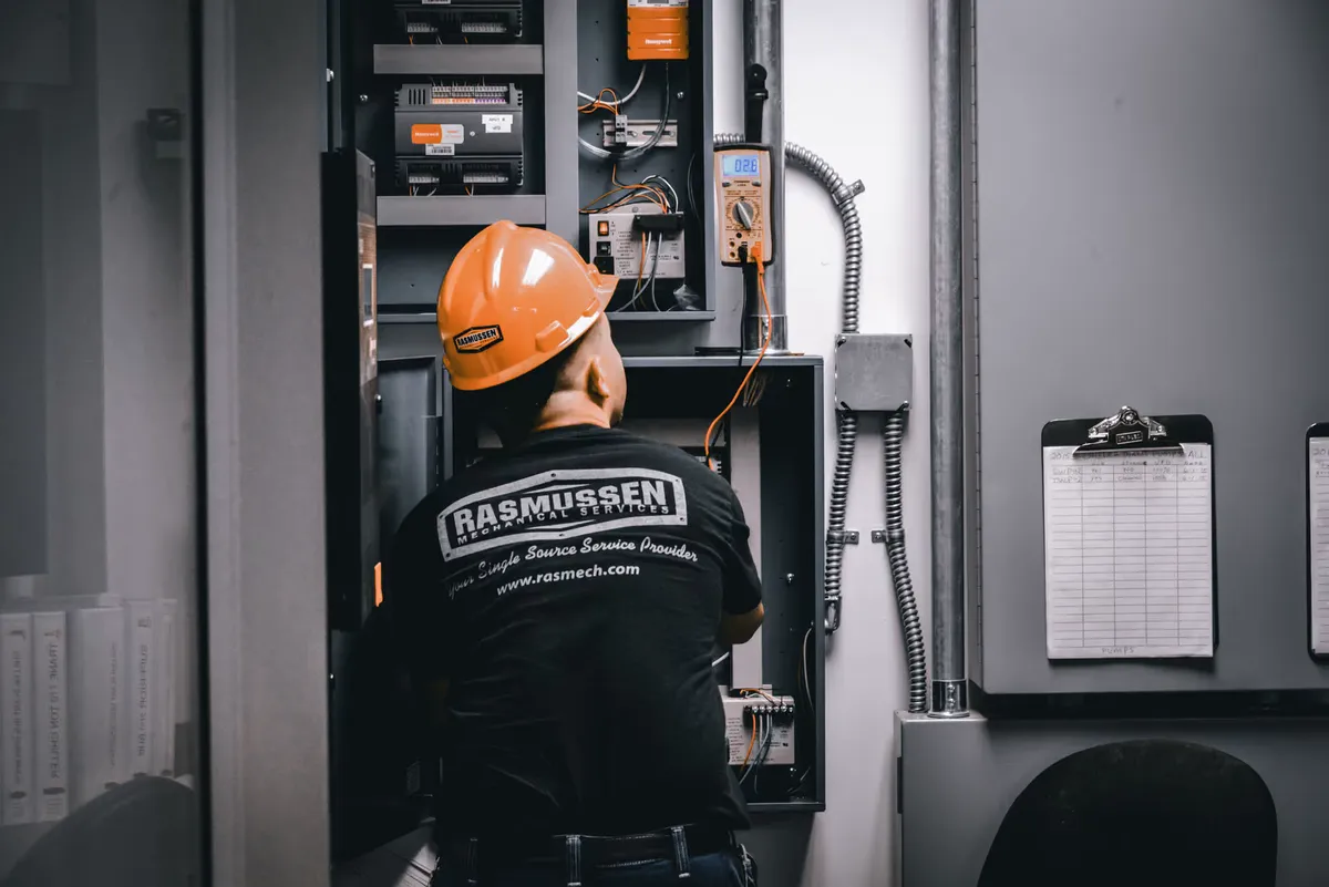 Technician installing and programming a building automation control panel at Rasmussen Mechanical Services.