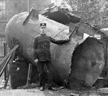 Police officer standing in front of a boiler that has exploded. 