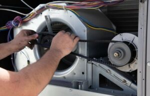 Fixing the fan belt of a HVAC unit by hand.